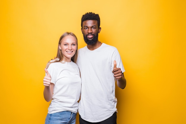Photo jeune couple diversifié avec les pouces vers le haut isolé sur mur jaune