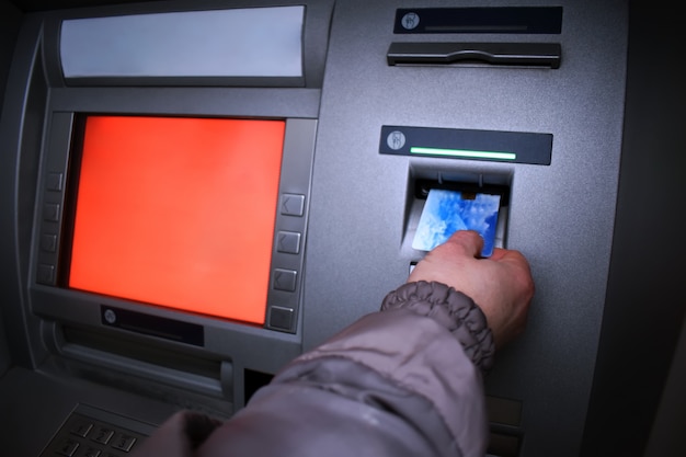 Photo jeune femme retire de l'argent de la carte de crédit au guichet automatique