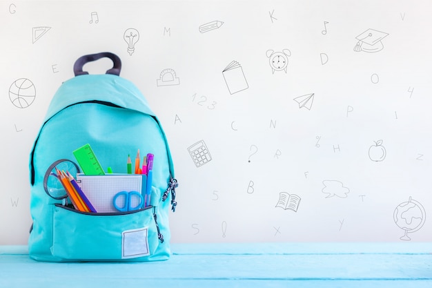 Photo retour à l'école. sac à dos scolaire turquoise avec papeterie sur table.