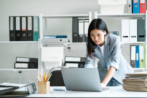 Młoda azjatycka bizneswoman pracująca w biurze przy użyciu laptopa