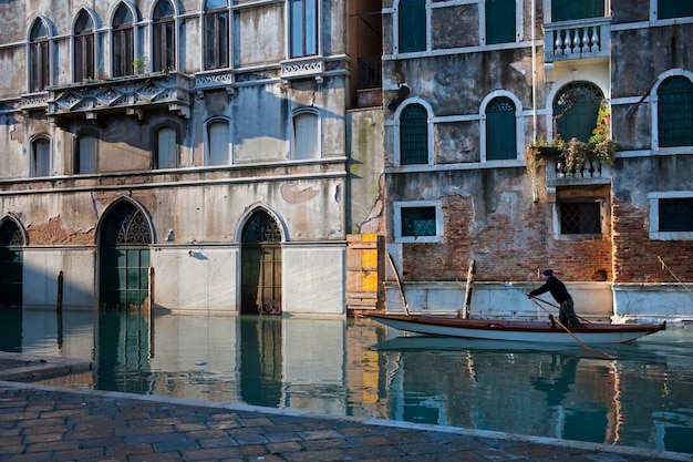 Zdjęcie człowiek wiosłujący łódź w kanale przeciwko budynkowi
