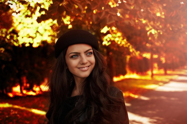 Kobieta w czarnym kapeluszu na tle jesiennych liści