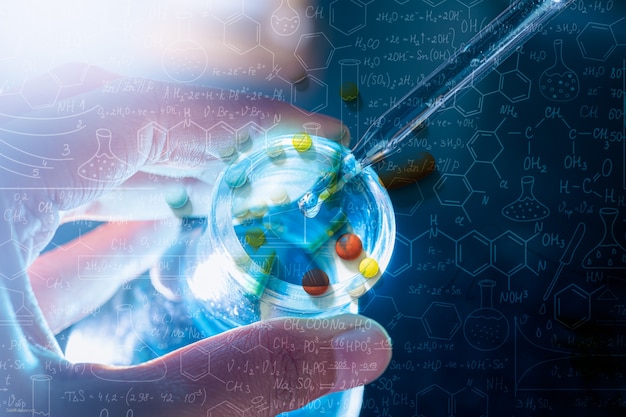 Zdjęcie ręka naukowca trzymająca kolbę ze szkłem laboratoryjnym i probówkami w tle laboratorium chemicznego