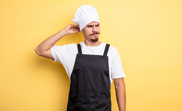 Zdjęcie szef kuchni czuje się zakłopotany i zdezorientowany, drapiąc się po głowie