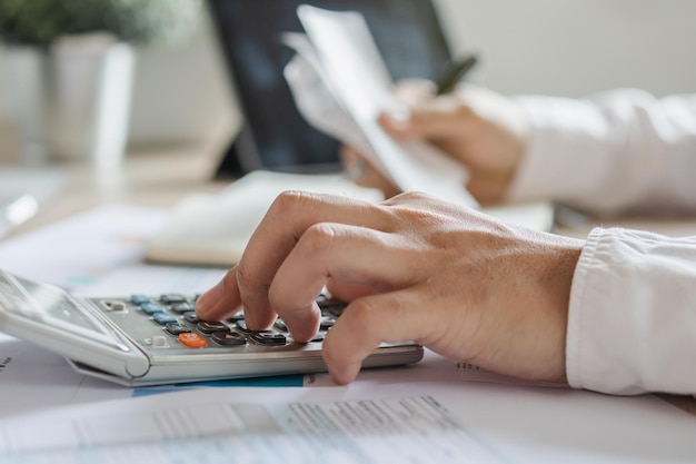 Zdjęcie zbliżenie dłoni azjatycki młody biznesmen mężczyzna naciskając kalkulator do obliczania dochodów i wydatków podatkowych karty kredytowej dla płatności lub wypłaty w domowym biurze koncepcja finansów finansowych