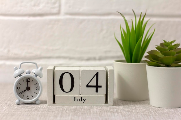 4th of July on wooden calendar and alarm clock on table Independence day concept