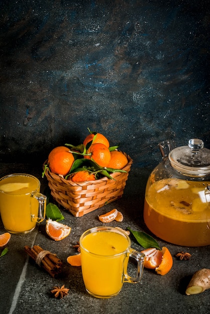 Мандариновый имбирный чай с корицей и анисом, с ингредиентами, на темном каменном фоне, копия пространства