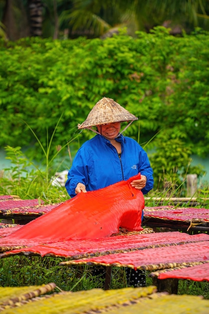 Фото Тай нинь, ветнам, 06 иуля 2023 фокус женщина из традиционной деревни, делающая красочную желе. они сушили свежее желе на деревянной решетке для рынка. концепция стиля жизни
