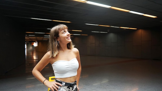 Фото Подростковая девушка отворачивается, стоя в освещенной подземной дорожке.