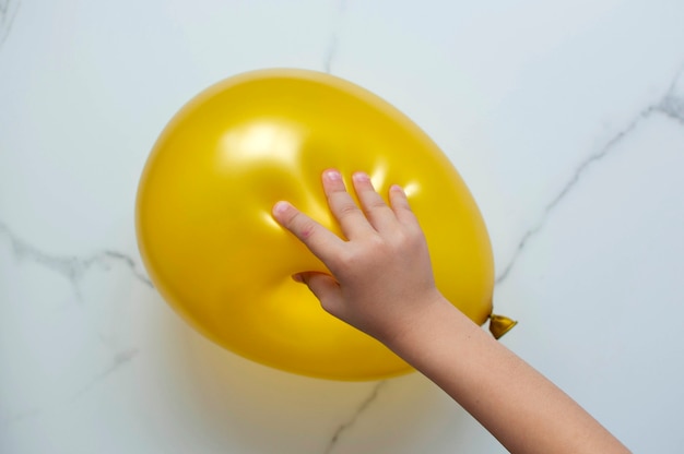 Фото Рука ребенка играет в тактильную развивающую игру, пытается лопнуть воздушный шарик.