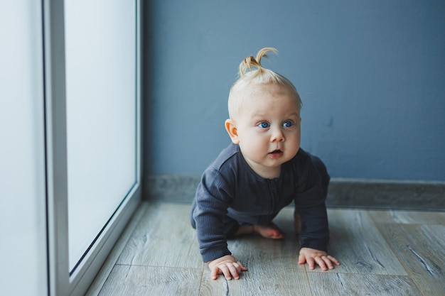 Фото Ребёнок учится ходить маленький мальчик в семь месяцев с хвостом на голове ребенок сидит на полу и улыбается