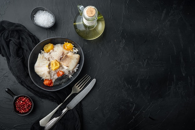 Рыба тилапия с рисом басмати и помидорами черри, в миске, на черном столе, вид сверху