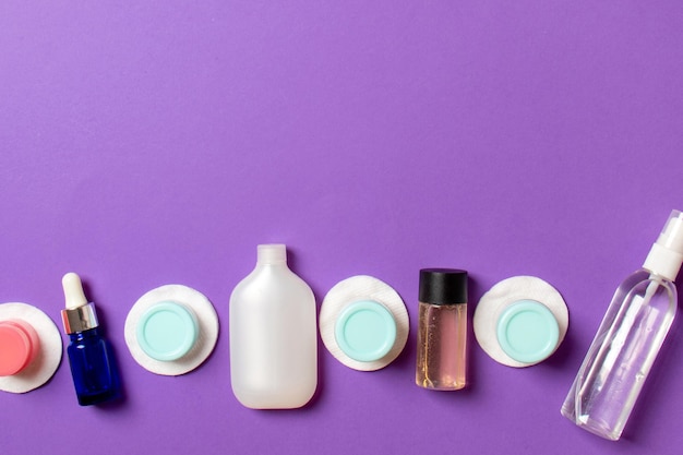 Photo top view composition of small travelling bottles and jars for cosmetic products on colored background facial skin care concept with copy space for your design