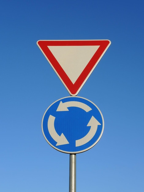Twee verkeersborden op dezelfde paal Geef voorrang en blauwe rotonde kruispunt weg