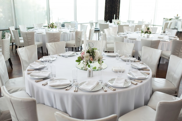 Сервировка свадебного стола украшена живыми цветами.