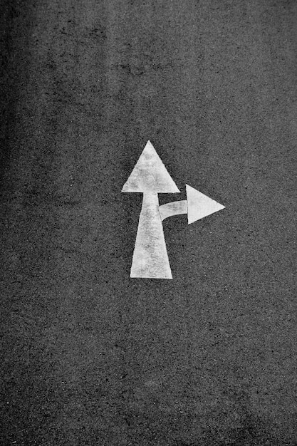 White arrow painted on asphalt road (Go straight and turn right)