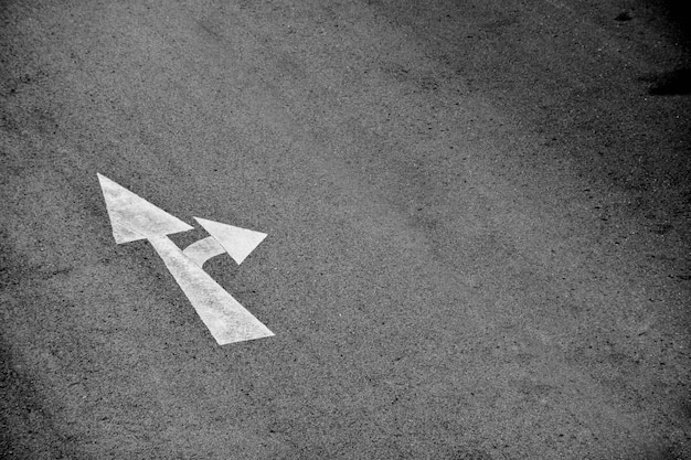 White arrow painted on asphalt road