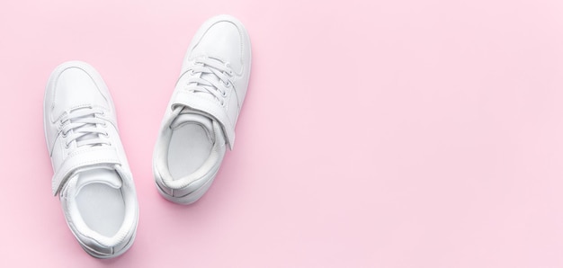 Белые кроссовки на розовом фоне