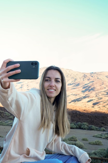 Фото Женщина делает селфи с мобильного телефона перед горой тейде
