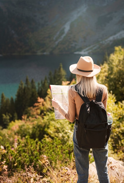 Фото Путешественник женщина в шляпе и глядя на удивительные горы и озеро, концепция путешествия страсть к путешествиям. озеро морской глаз в польских татрах.