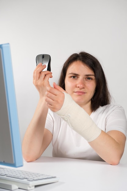 A woman with an elastic bandage on her wrist sits in front of a computer