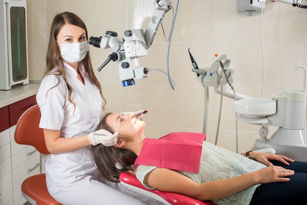 Женщина стоматолог в своем кабинете лечения пациентки