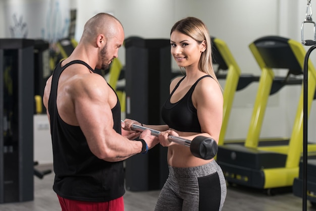 Photo woman exercising biceps with her personal trainer