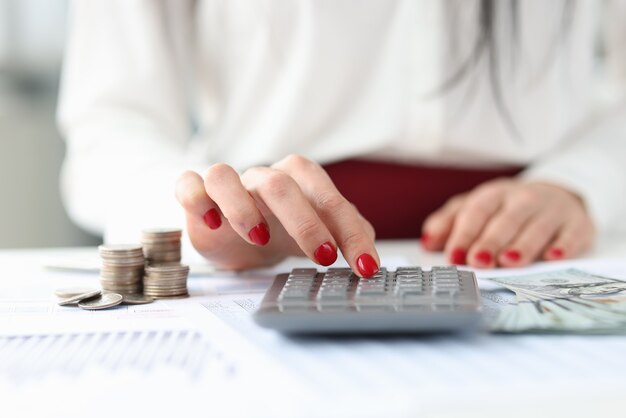 Фото Женщина сидит за столом с деньгами и рассчитывает на калькулятор