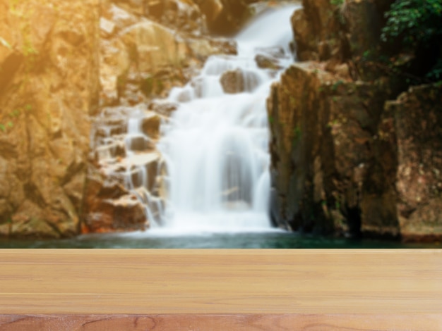 Wooden board empty table blur waterfall in forest background.