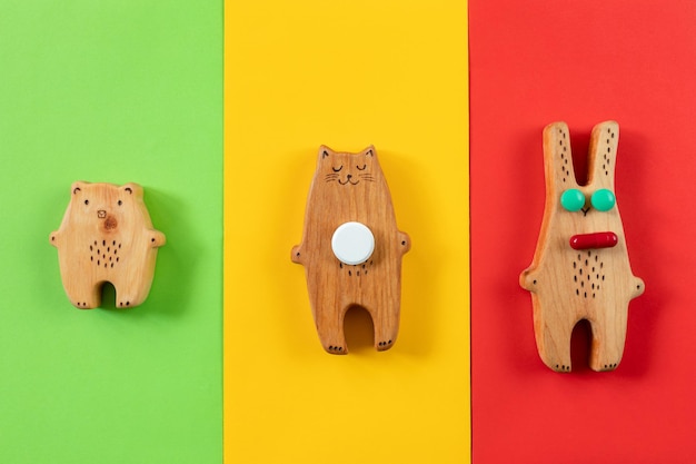 Foto statuine in legno di un orso, una lepre e un gatto con pillole su sfondi colorati. il concetto di medicina dei bambini