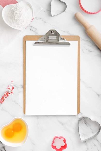 Wooden tablet mock up with white paper space for text, around ingredients for baking cookies. Concept cooking with love, cooking for your loved ones, baking for valentines day. Copy space. Top view