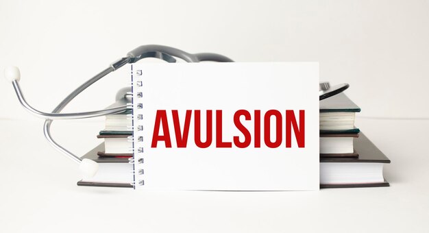 The word avulsion written on a white notepad on a white background near a stethoscope