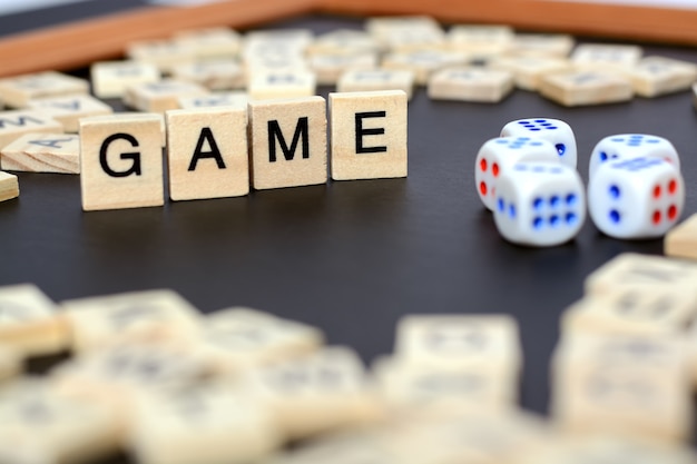 Фото Слово игра с деревянными буквами на черном доске с кубиками и буквой в кругу