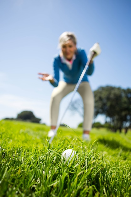 Взволнованный женщина-гольфист, глядя на мяч для гольфа