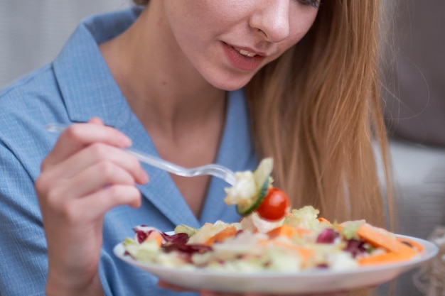 Photo young woman is eating salad at home diet concept disgruntled person depression from having to diet lack of fat in the diet