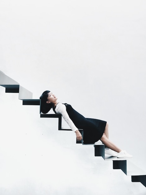 Фото Молодая женщина лежит на лестнице на белом фоне