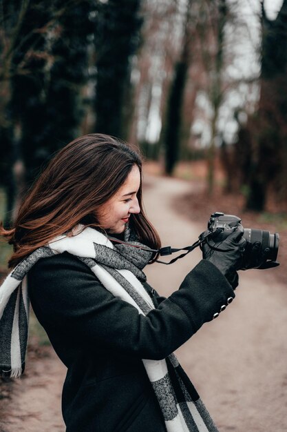 Фото Молодая женщина фотографирует с камерой в лесу