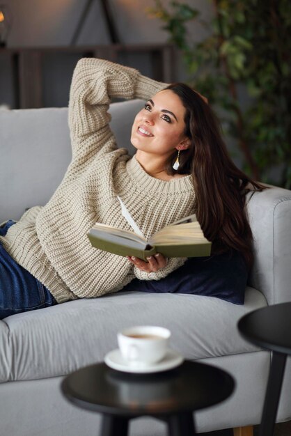Фото Молодая женщина сидит на диване дома.