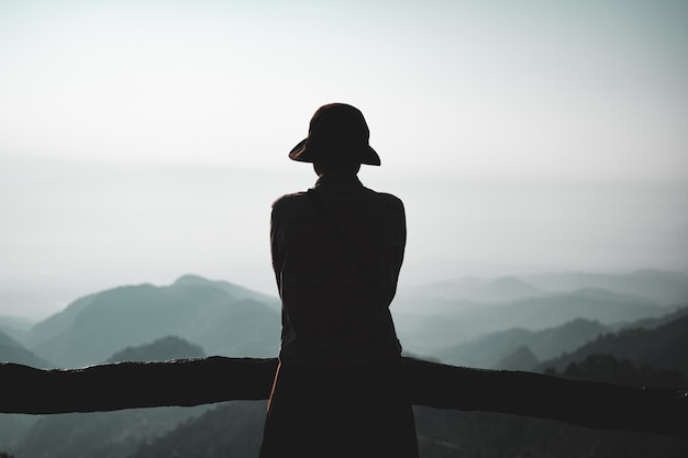 Фото Молодая женщина, стоящая в одиночестве на открытом воздухе с дикими лесными горами на фоне
