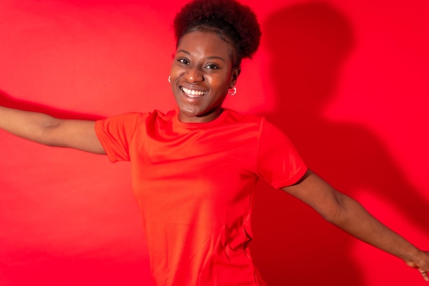 Photo young african american woman isolated on a red background smiling and dancing studio shoot