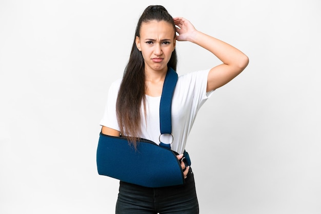 Young Arabian woman with broken arm and wearing a sling over isolated white background having doubts