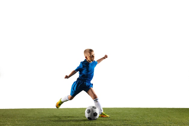 Молодой мальчик в футболе или футболисте в спортивной одежде, делая финт или удар мячом по воротам на белой стене.