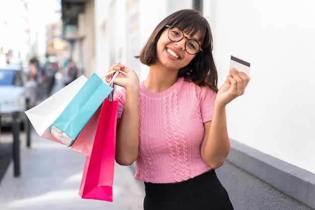 Young brunette woman in the city holding shopping bags and a credit card