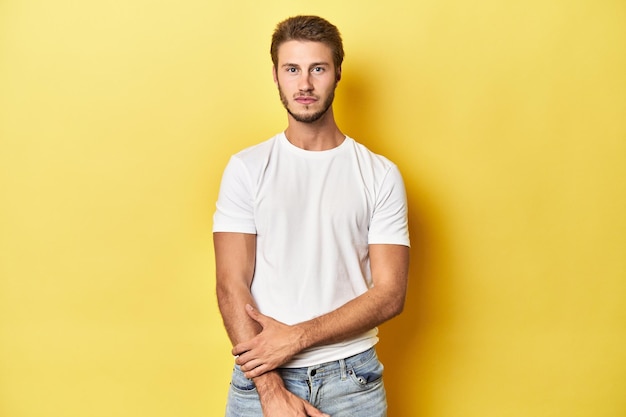 Photo young caucasian man posing on a vibrant yellow studio backdrop