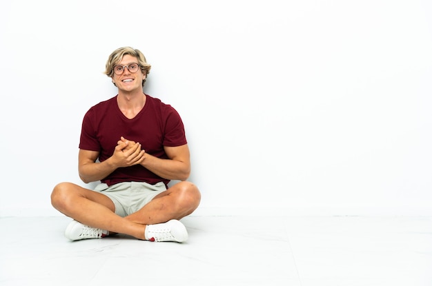 Photo young english man sitting on the floor laughing