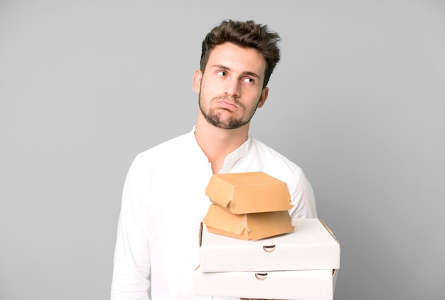 Young handsome man isolated with fast food mock up boxes delivery and take away concept
