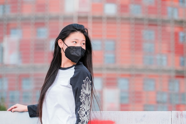 Young happy asian girl wearing medical face mask on city street