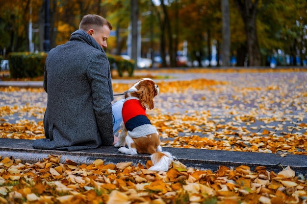 Молодой человек гуляет с собакой в осеннем парке