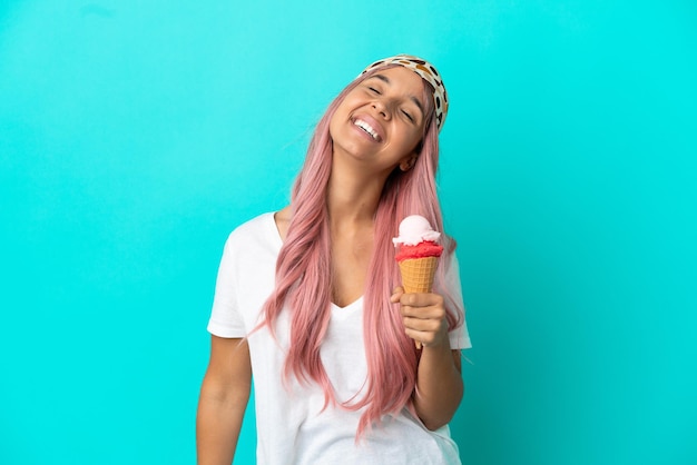 Молодая женщина смешанной расы с мороженым корнет, изолированные на синем фоне смеясь