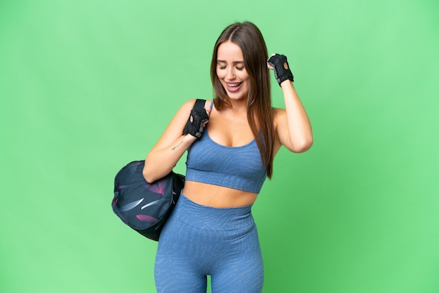 Фото Молодая спортивная женщина со спортивной сумкой на изолированном фоне цветного ключа празднует победу